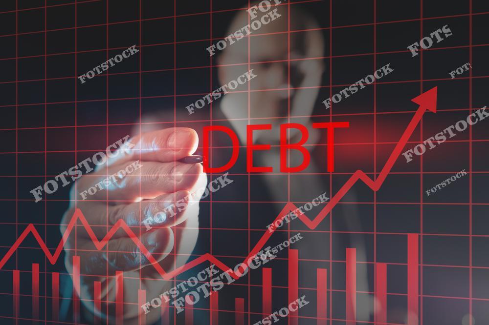 На изображении изображена рука, указывающая на слово "DEBT" (долг) на фоне графика с растущими барьерами и стрелкой, что символизирует рост долговой нагрузки и финансовые проблемы. Это отражает тревожный тренд увеличения долгов.